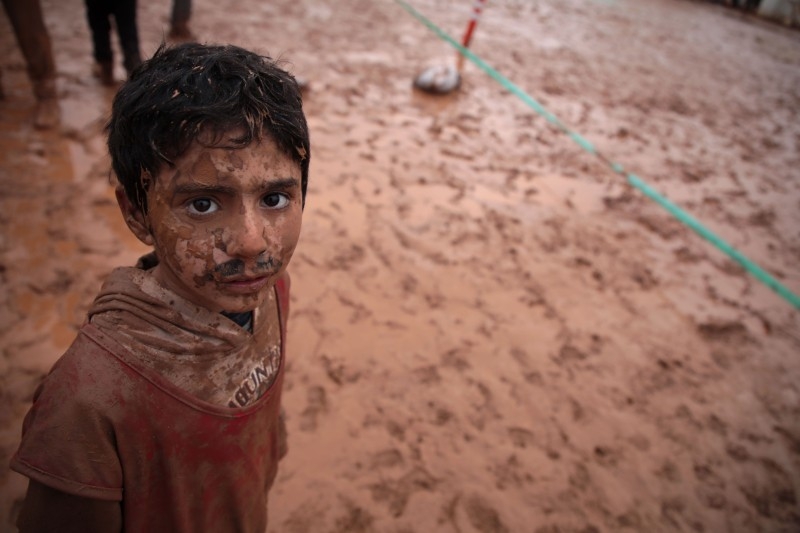 A Syrian boy plays a game of football organized by local activists, in a muddy field in a camp for the internally displaced west of Sarmada town in Syria's northwestern province of Idlib, on Thursday. — AFP
