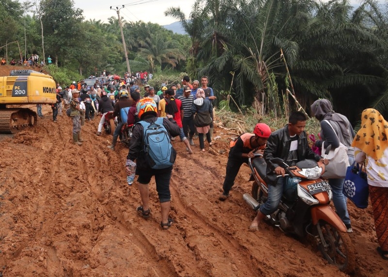 Villagers commute through the mud in a landslide area at Sukaraksa village in Bogor, after torrential rains began to hit the area. Indonesian rescue teams flew helicopters stuffed with food to remote flood-hit communities on Saturday as the death toll from the disaster jumped to 60 and fears grew about the possibility of more torrential rain. — AFP