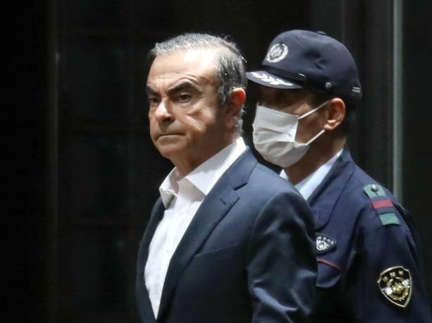 This file photo taken on April 25, 2019 shows former Nissan chairman Carlos Ghosn (L) being escorted as he walks out of the Tokyo Detention House following his release on bail in Tokyo. -AFP