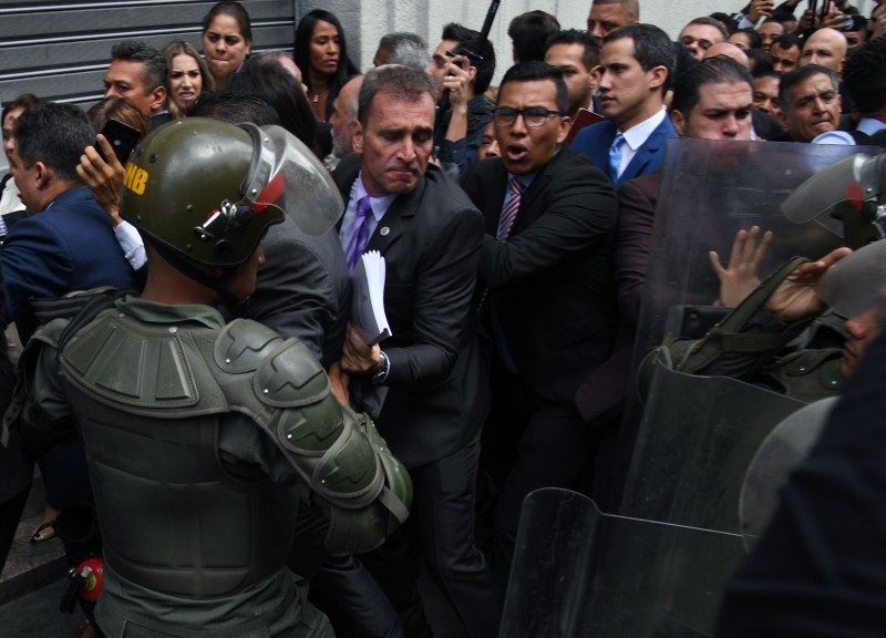 Venezuelan opposition leader and self-proclaimed acting president Juan Guaido (blue suit) heads towards the entrance to the the National Assembly while journalists struggle with Bolivarian National Guard members after being banned from entering, in Caracas, on Sunday. — AFP