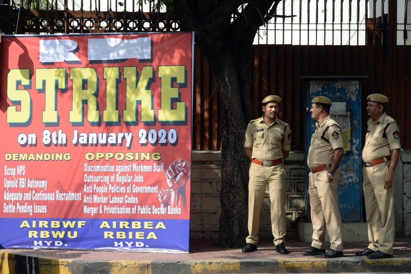 Police stand beside a poster board announcing a strike, outside the Reserve Bank of India (RBI), during a nationwide general strike called by trade unions aligned with opposition parties to protest the Indian government's economic policies in Hyderabad on Wednesday. -AFP