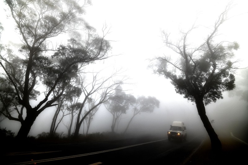 A car makes its way through thick fog mixed with bushfire smoke in the Ruined Castle area of the Blue Mountains, some 75 kilometers from Sydney, on Saturday. -AFP