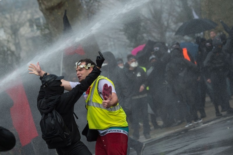 'Yellow Vest' (gilets jaunes) anti-government movement protester are soaked by a police water canon as he takes part of a nationwide multi-sector strike against the French government's pensions overhaul, in Nantes, western France, on Saturday. — AFP