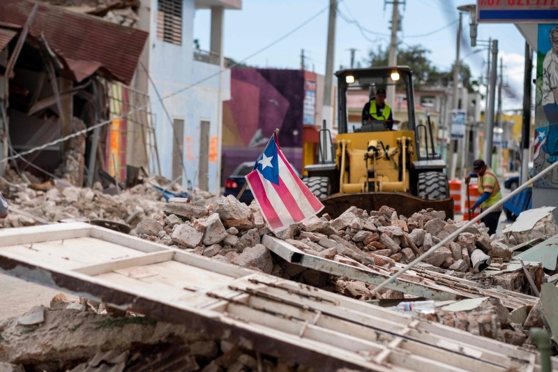 A Puerto Rican flag waves on top of a pile of rubble as debris is removed from a main road in Guanica, Puerto Rico, in this Jan. 8, 2020 file photo. — AF{