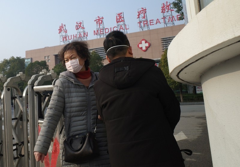A man holding his daughter leaves the Wuhan Medical Treatment Center, where a man who died from a respiratory illness was confined, in the city of Wuhan, Hubei province, on Sunday. -AFP