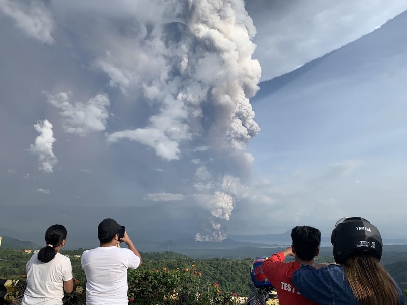 People take photos of an explosion from the Taal volcano as seen from the town of Tagaytay in Cavite province, southwest of Manila, on Sunday. -AFP