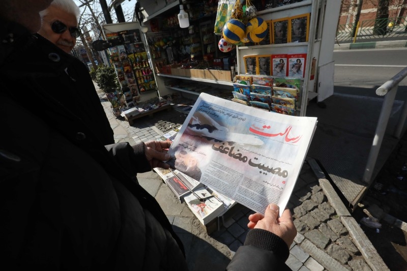 An Iranian man checks a local newspaper headline that reads 