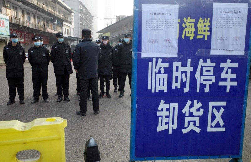 Security guards stand in front of the closed Huanan wholesale seafood market, where health authorities say a man who died from a respiratory illness had purchased goods from, in the city of Wuhan, Hubei province, on Sunday. — AFP