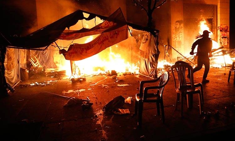 An anti-government protester tries to extinguish his tent reportedly set on fire by the private unit of the parliament guards in Beirut, Lebanon, on Saturday night. -Courtesy photo