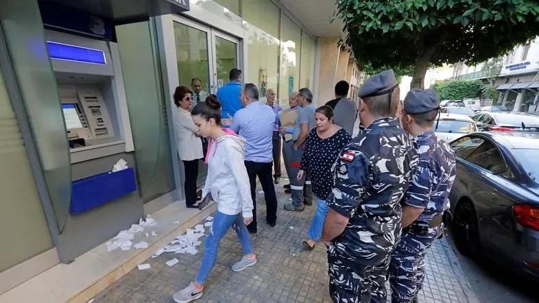 People await to enter a bank that has just reopened in the center of the Lebanese capital Beirut. — AFP