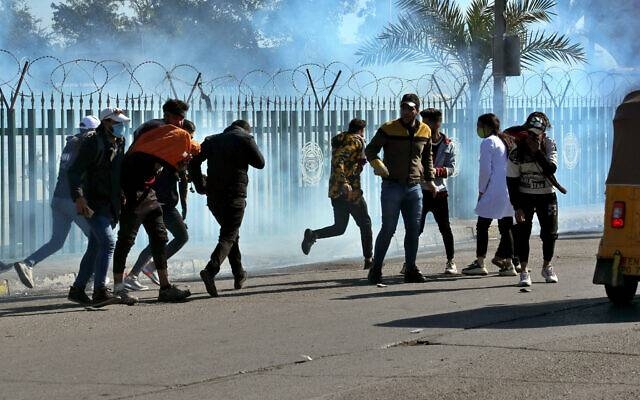 Anti-government protesters run as security forces fire tear gas to disperse them during clashes in Baghdad, Sunday. Courtesy photo