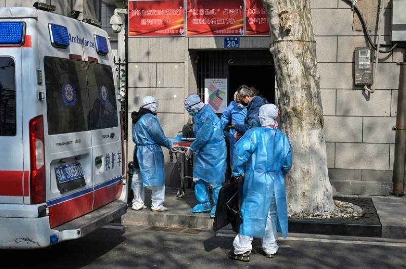 Medical staff in protective clothing carry a suspected virus patient from an apartment in Wuhan. — AFP