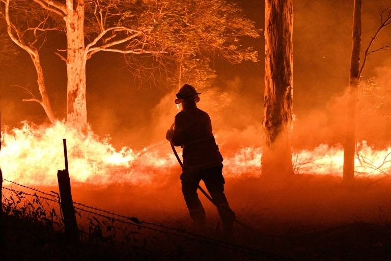 Fire crews battling a large blaze on the Australian capital's southern flank said it was no longer at emergency level as temperatures fell back from heatwave highs and rain was forecast. — AFP