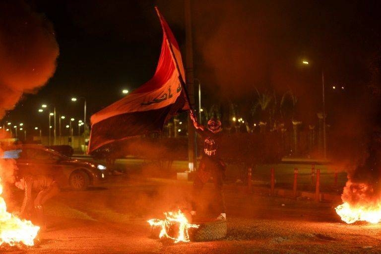 Young men with their faces wrapped in checkered scarves torched car tires in Najaf in anger at the nomination of Mohammad Allawi as Iraq's prime minister. — Courtesy photo