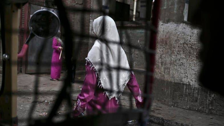 An Egyptian woman seen from a motorized rickshaw walks on a street in Cairo, near the home of 12-year-old girl who died undergoing the procedure of FGM. — Courtesy photo