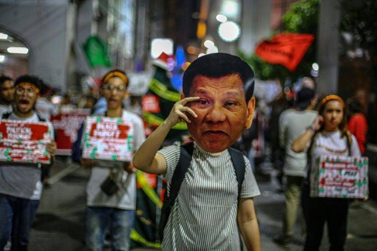 A human rights advocate holds up a mask featuring Philippine President Rodrigo Duterte during a rally in Manila. — AFP