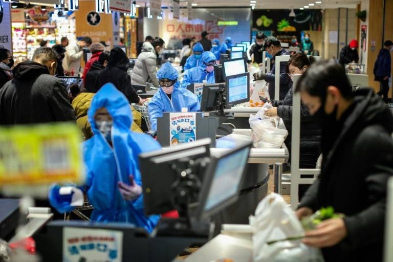 Tellers in full protective masks process shopping at a supermarket in Shenyang in China's northeastern Liaoning province. — AFP