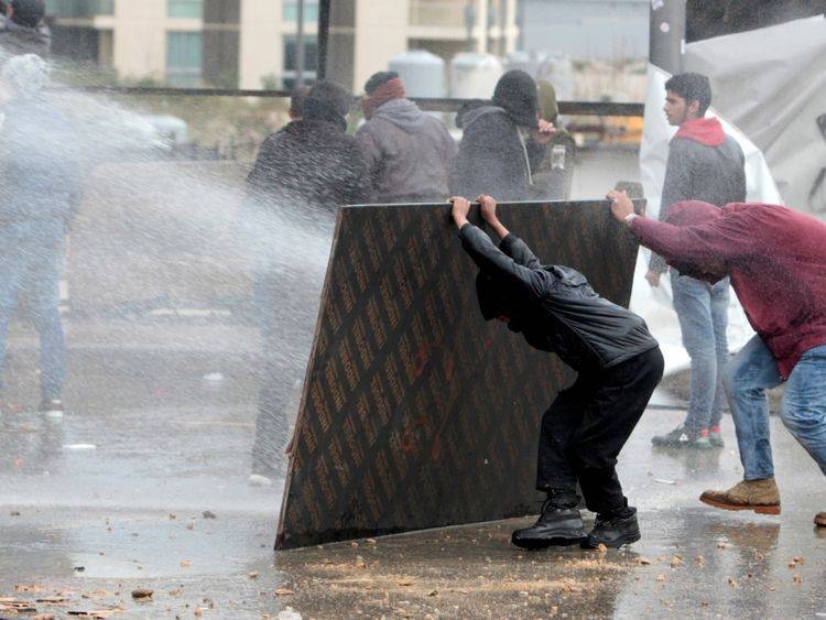 Demonstrators take cover from water cannon during a protest in Beirut, Tuesday. — Courtesy photo