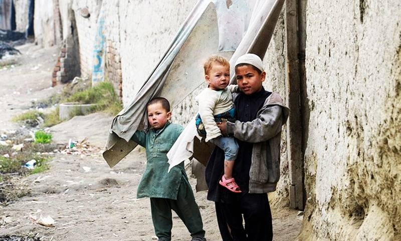 Afghan refugee children stand in front of their home in a refugee camp in Peshawar, Pakistan, in this file photo. — AFP