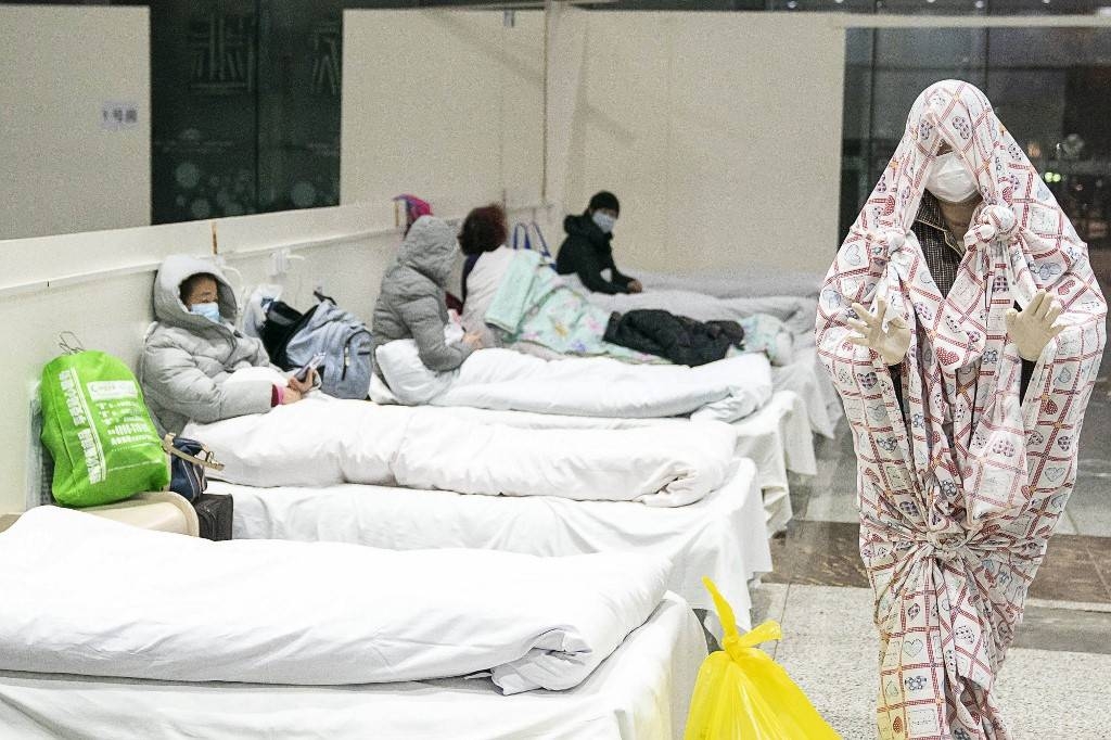 A patient, right, is seen covered with a bed sheet at an exhibition center converted into a hospital as it starts to accept patients displaying mild symptoms of the novel coronavirus in Wuhan in China's central Hubei province in this Feb. 5, 2020 file photo. — AFP