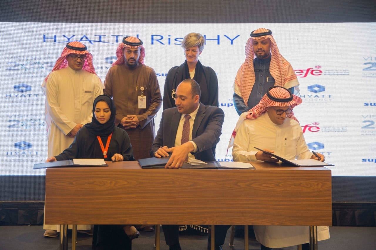 The photo shows the signing ceremony of Hyatt Regency Riyadh Olaya's partnership with the Hotel and Tourism Management Institute Switzerland — Saudi Arabia (HTMi), and the international non-profit Education for Employment (EFE). 