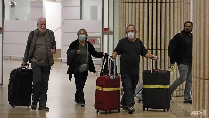Passengers wearing protective masks walk at the arrival hall of Ben Gurion International Airport in Israel. — Courtesy photo 