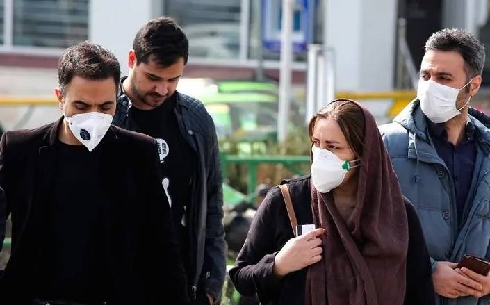 Iranians, with some wearing masks, wait to cross the street in Tehran in this Feb. 22, 2020, photo. — AFP
