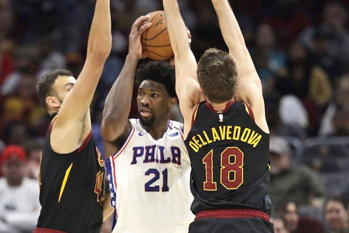 Philadelphia 76ers' Joel Embiid, center, squeezes between Cleveland Cavaliers' Ante Zizic, left and Matthew Dellavedova in the first half of an NBA basketball game, Wednesday in Cleveland.