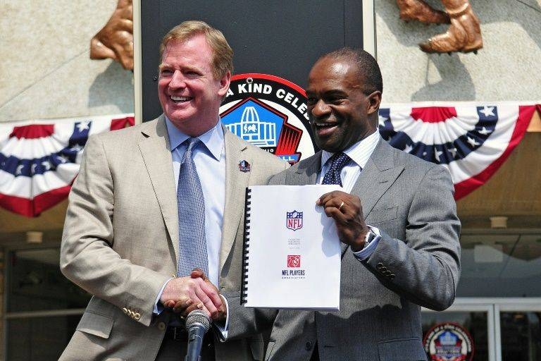 NFL commissioner Roger Goodell, left, and NFL Players Association executive director DeMaurice Smith shake hands while displaying the 10-year NFL collective bargaining agreement reached in 2011. — AFP
