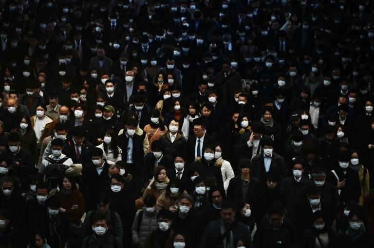 Mask-clad commuters make their way to work during morning rush hour at the Shinagawa train station in Tokyo. — AFP