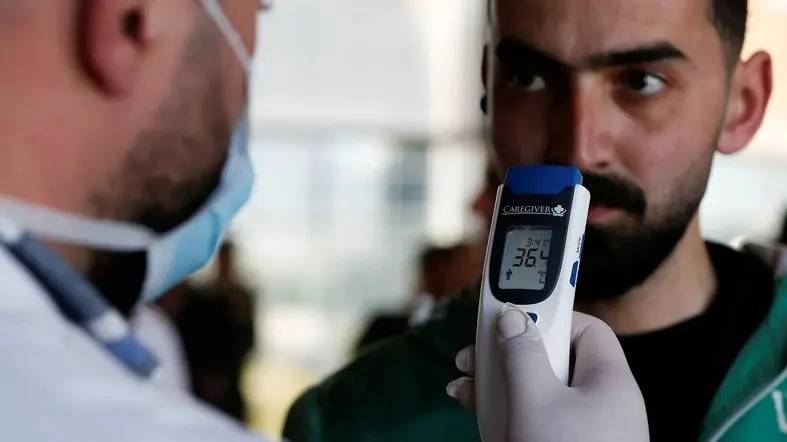 A medical staff member checks the temperature of a reporter during a media tour at the Queen Alia International Airport in Amman, Jordan. — Courtesy photo