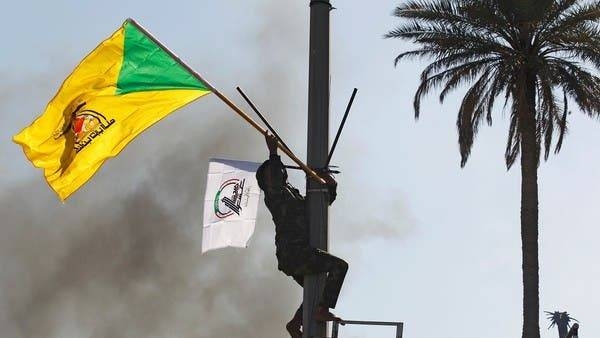 A member of the PMU militias holds a flag of Kataib Hezbollah militia group during a protest in Baghdad to condemn airstrikes on their bases. -- Courtesy photo