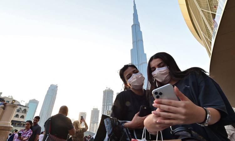 Women wearing protective masks pose for a selfie in front of Burj Khalifa in Dubai in this file picture. — Courtesy photo