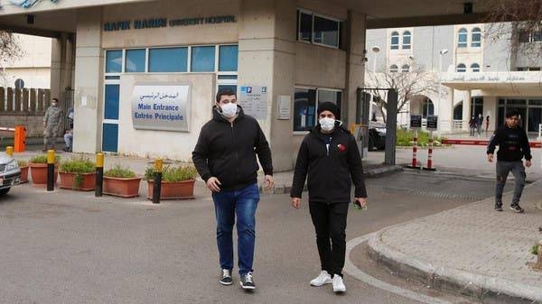 People wearing face masks walk outside Rafik Hariri hospital in Beirut, where Lebanon's first coronavirus case is being quarantined. -- File photo