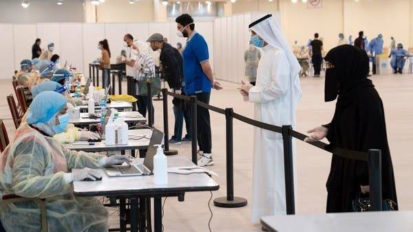 Kuwaitis, arriving from Europe, stand a safe distance apart to give their details to ministry of health officials in a makeshift coronavirus testing center. -- File photo