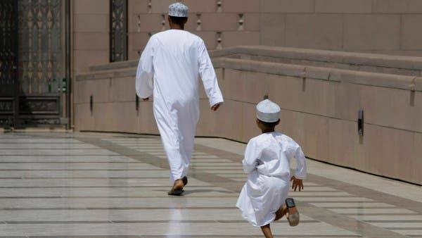 An Omani boy runs after his father as they rush to Sultan Qaboos Grand Mosque in Muscat. -- File photo
