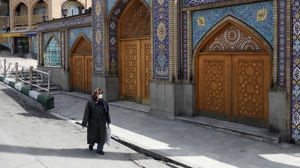 A woman wearing a protective face mask and gloves walks past a building housing the grave of Imamzadeh Saleh in Tehran. -- File photo
