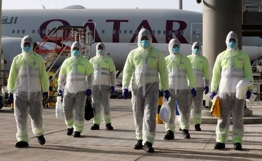 Employees of Qatar Aviation Services (QAS), wearing protective gear as a safety measure during the COVID-19 pandemic, walk along the tarmac after sanitizing an aircraft at Hamad International Airport in the Qatari capital Doha. -- Courtesy photo