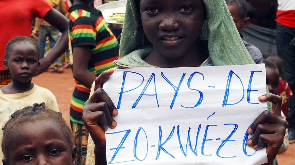 A young girl holds a sign that says Zo Kwe Zo, Central African Republic's national motto, meaning all human beings are equal. — UN file photo