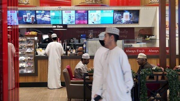 Omani men pass in front of Canadian cafe and bake shop Tim Hortons in City Center Mall in Muscat. -- File photo
