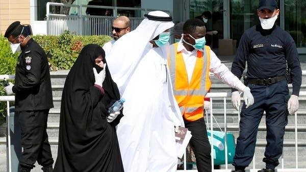 ​​​​​​​Qatari police stand outside a hotel in Doha as a medical worker walks alongside people wearing protective masks. -- File photo
