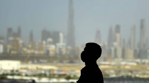 A man wears a face mask against the backdrop of Dubai. -- File photo
