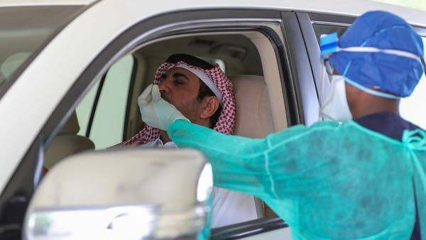 A health worker collects a swab from a man at a drive-thru coronavirus testing service in Doha. -- File photo
