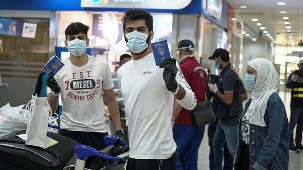 Kuwaiti boys wearing protective face masks and quarantine tracking bracelets pose for the camera as they hold up their passports upon arrival from Amman to Kuwait Airport. -- Courtesy photo