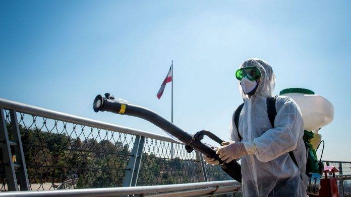 A firefighter in protective clothing, mask and goggles, sprays disinfectant on Tabia't bridge pedestrian overpass in Tehran, Iran. -- File photo
