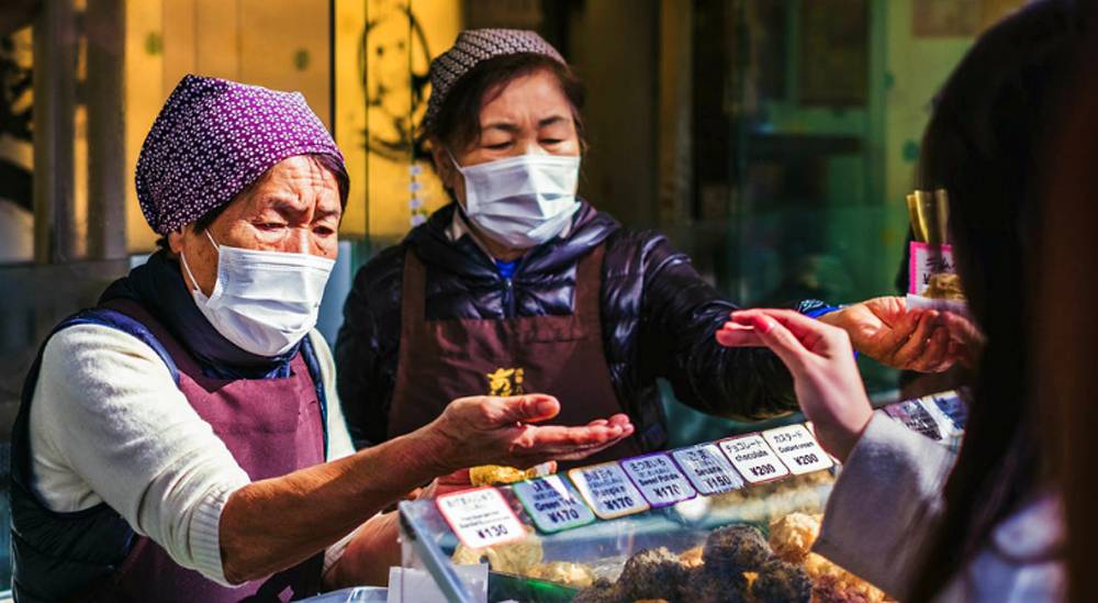 Vendors wear face masks at a food market in Japan. — courtesy Unsplash/ Jérémy Stenuit