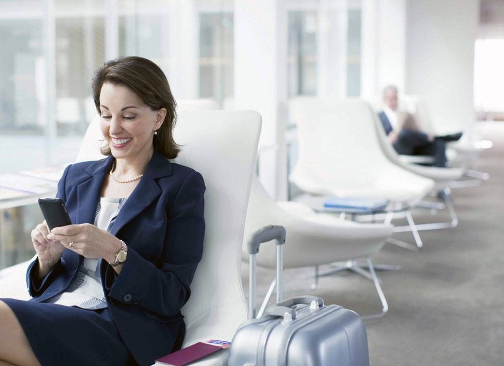 Businesswoman with luggage sitting in airport waiting area.