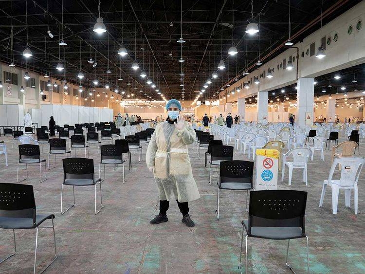 A volunteer who directs visitors at a coronavirus testing center, gestures at the Kuwait International Fairgrounds in Mishref in this file photo.
