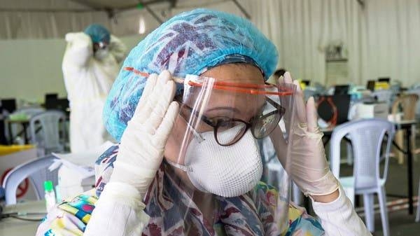 A doctor adjusts her protective face shield at a makeshift field testing center at Kuwait Airport in this file photo.
