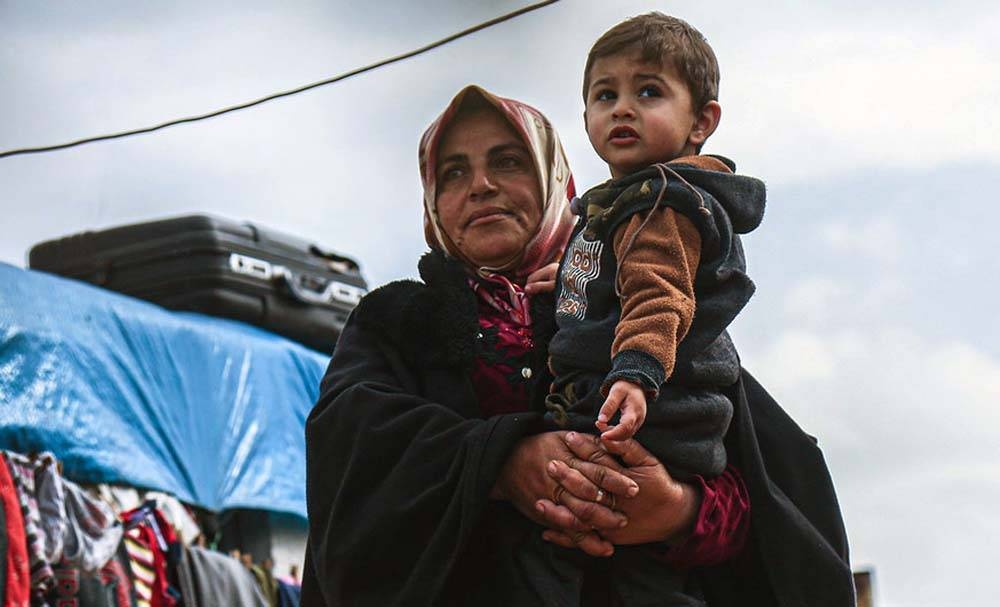 A widow holds her grandson in a displaced persons camp in northern Idlib Governorate, Syria. — courtesy OCHA/Steve Hafez